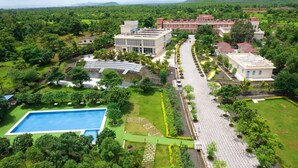 Luchtbeeld van een resort met een zwembad, aangelegde tuinen en gebouwen met rode daken.