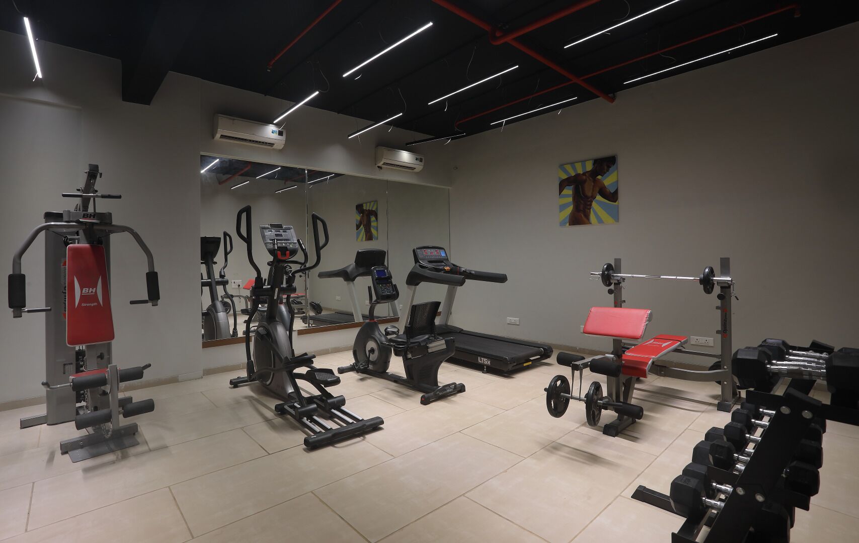 Ett gym med olika typer av träningsutrustning, inklusive löpband, crosstrainer och styrketräningsmaskiner.