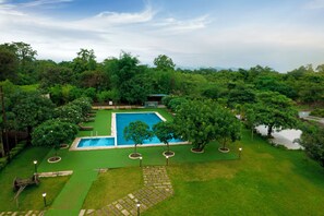 A swimming pool surrounded by lush greenery, with a clear sky above.