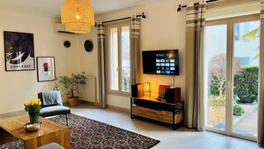 Un salon avec un téléviseur à écran plat, une plante en pot, un canapé et une table basse.