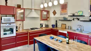 A modern kitchen with red cabinetry, a wooden dining table, and a built-in oven. - 2 Storey House, a/c❄️, garden, central Bergerac, spacious & bright. Parking privé (Bergerac)