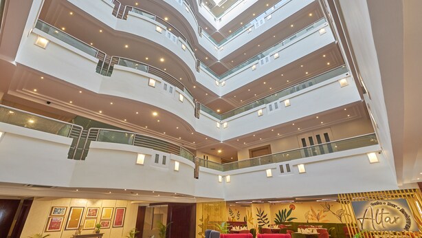 A spacious lobby with multiple seating areas, a high ceiling with a skylight, and a restaurant area.