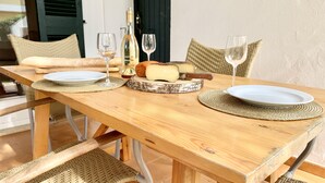 Una mesa de madera con platos, vasos y una tabla de quesos.