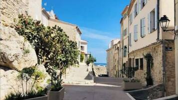 Un vicolo stretto con edifici in pietra, piante in vaso e un cielo azzurro limpido.