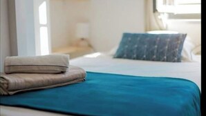 Ein ordentlich gemachtes Bett mit blauer Bettdecke und zwei gefalteten Handtüchern.