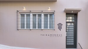 A building entrance with a sign reading "THIRAMENOUS RESIDENCE" and a window with metal bars. - THIRAMENOUS RESIDENCE - SIX BEDROOM HOUSE with Rooftop Hot Tub (Athina)
