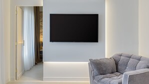 A modern living room with a flat-screen TV mounted on the wall, a grey sofa, and a minimalist design. - THIRAMENOUS RESIDENCE - SIX BEDROOM HOUSE with Rooftop Hot Tub (Athina)