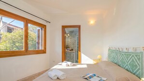 A bedroom with a bed, towels, a magazine, a window, and a view of the outside. - Villetta Franca 100m From The Beach (Golfo Aranci)