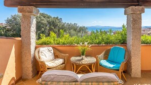 A covered outdoor seating area with wicker furniture and a view of the sea. - Villetta Franca 100m From The Beach (Golfo Aranci)