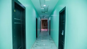 A corridor with a marble floor, teal walls, and black doors. - Emmy Hotels and Suites (Lekki)