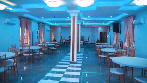 A spacious dining area with multiple tables and chairs, a checkered floor, and blue ambient lighting. - Emmy Hotels and Suites (Lekki)