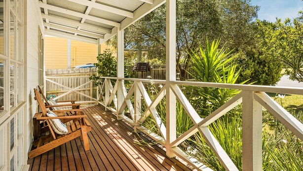A wooden deck with a railing, a birdhouse, and a bench. - Clifden Cottage in Cowes (Cowes)