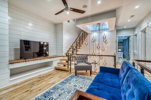 Relax in this stylish living space with a large flat-screen TV, comfortable sofa, and cozy seating area.