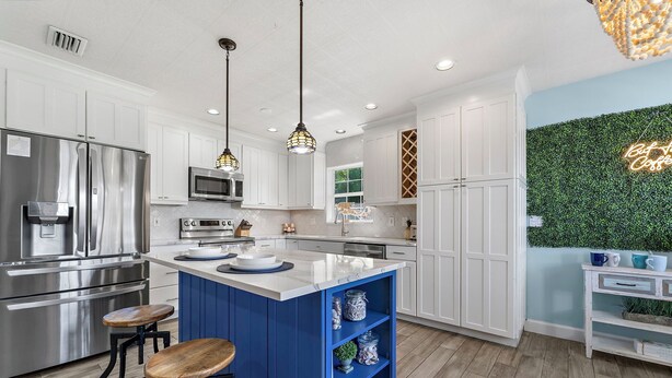A modern kitchen with white cabinetry, a blue island, stainless steel appliances, and a green wall accent. - ⚓Private pool home-Boat Dock-Arcade Games!⚓🌅 (Bradenton)