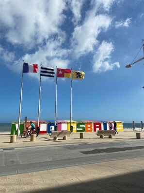 A beachside promenade with flags, benches, and a clear sky. - The Harbor and the Sea (Dunkerque)
