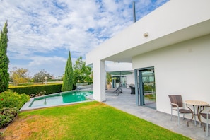 A modern outdoor pool area with a clear sky, a well-maintained lawn, and a patio with outdoor furniture. - Casa Blanca Magnificent Villa With Modern Design, walking distance to beach (Carvoeiro)