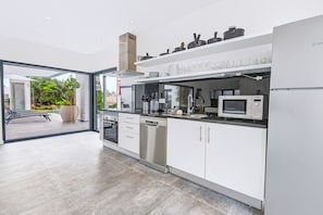 A modern kitchen with a dishwasher, oven, microwave, and a glass door leading to an outdoor area. - Casa Blanca Magnificent Villa With Modern Design, walking distance to beach (Carvoeiro)