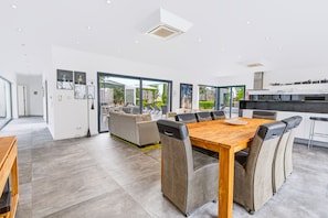 A modern kitchen with a dining area, large windows, and a view of the outdoors. - Casa Blanca Magnificent Villa With Modern Design, walking distance to beach (Carvoeiro)