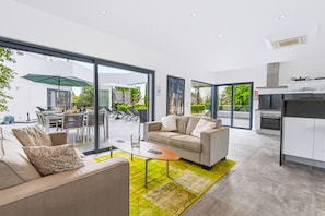 A modern living room with a sofa, coffee table, and a dining area with chairs and a table. - Casa Blanca Magnificent Villa With Modern Design, walking distance to beach (Carvoeiro)