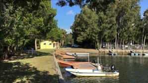 A dock with a boat, a small yellow building, and trees along a water body. - "Salty Siren" Mermaid Themed Room at Weeki Wachee Waterfront Adventure Retreat (Weeki Wachee)