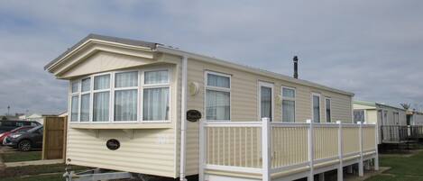A single-story mobile home with a white exterior and a fenced porch area.