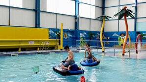 An indoor swimming pool with inflatable rides and a mural of tropical scenes. - Caravan -chapel, Skegness With Decking From March (Skegness)
