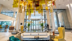 Un hall d’entrée spacieux avec un espace salon central, une porte tournante et un lustre moderne.