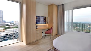 Une chambre d’hôtel moderne dotée d’un grand lit, d’un bureau avec un ordinateur, d’une télévision et offrant une vue sur la ville.