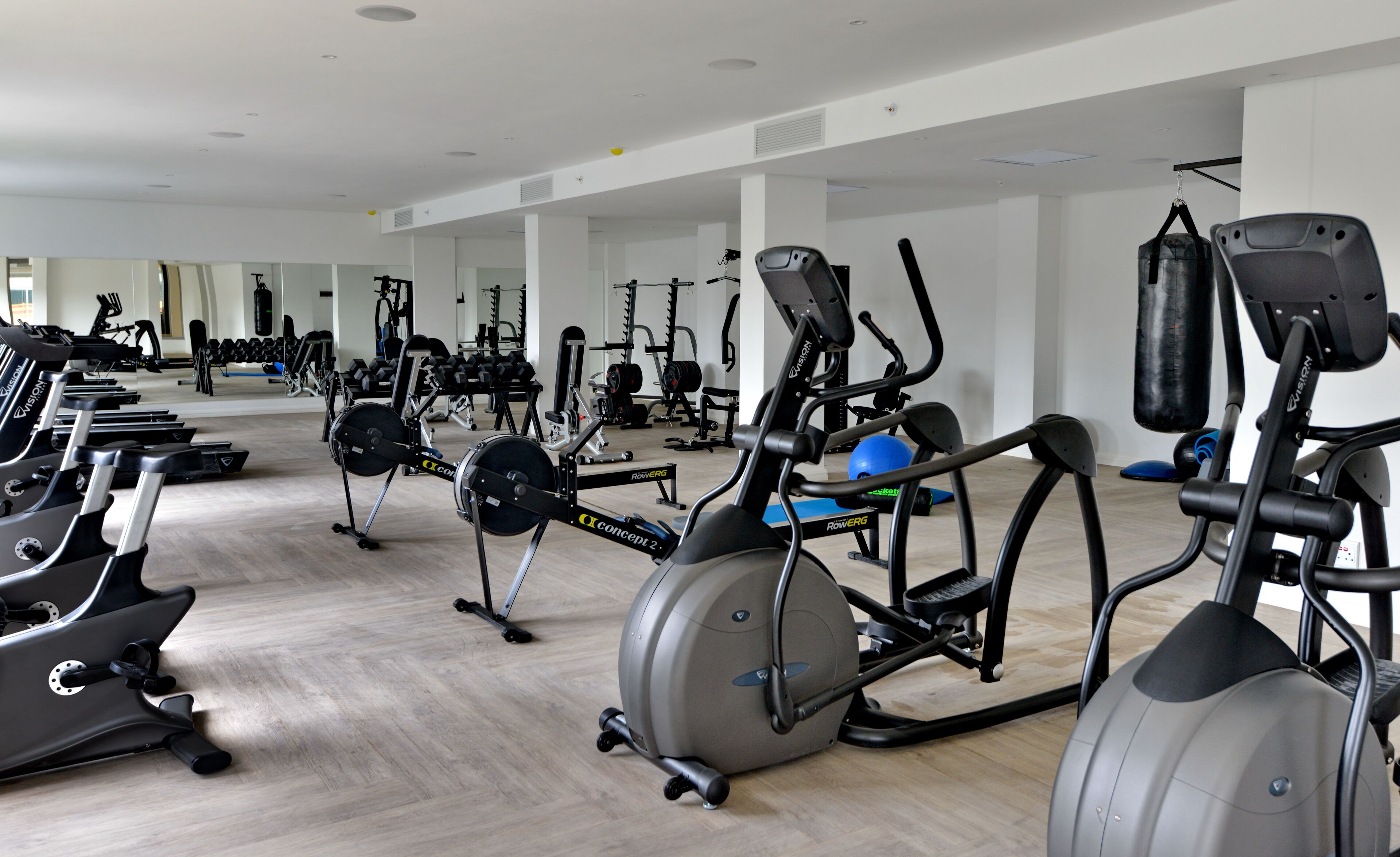 A gym with various exercise equipment including treadmills, elliptical machines, and weight machines.