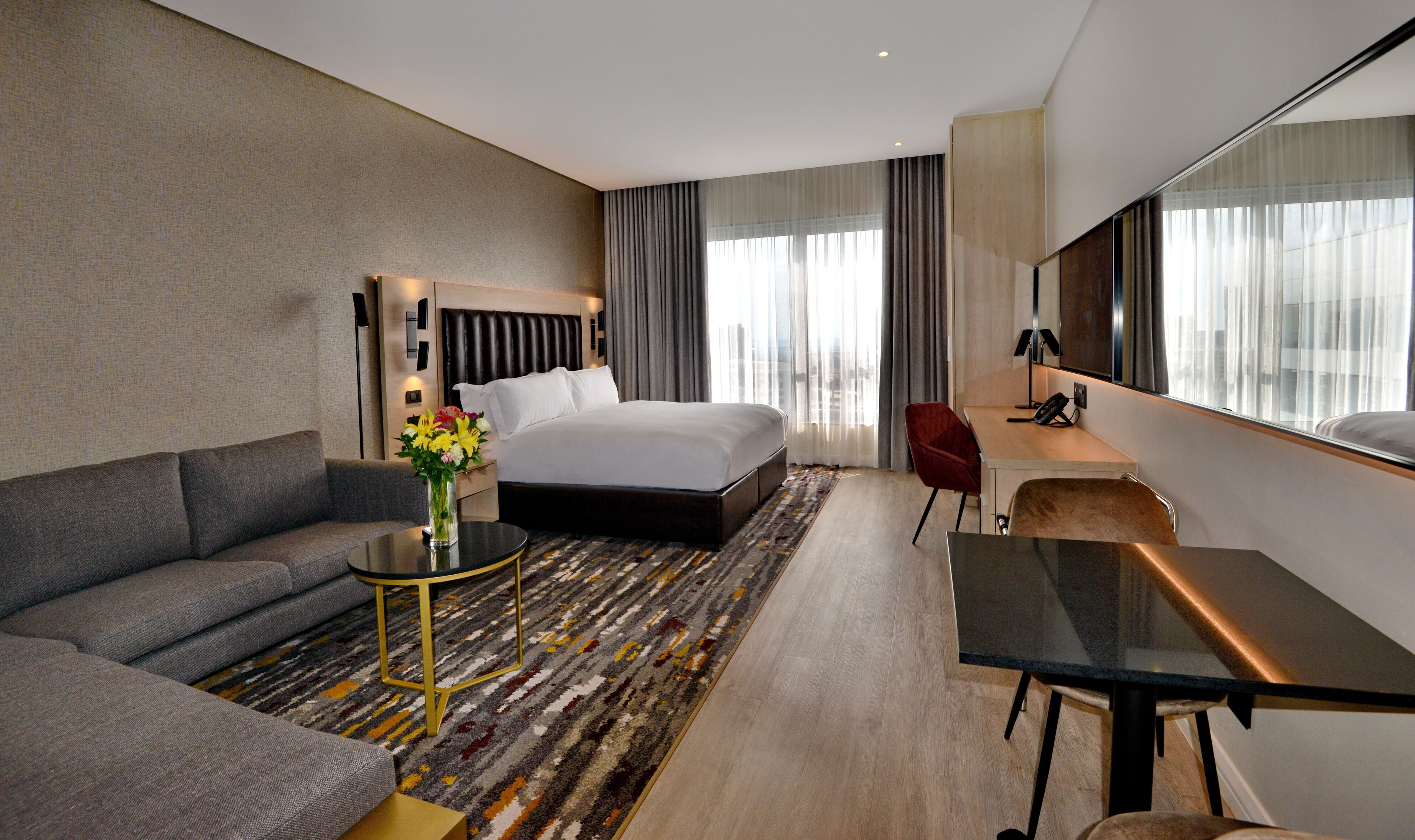 Una habitación de hotel con una cama, un sofá, un escritorio y un espejo grande.