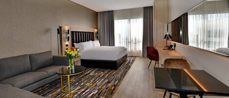 Una habitación de hotel con una cama, un sofá, un escritorio y un espejo grande.