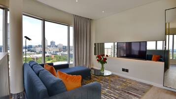 A modern living room with a large sofa, a coffee table, and a TV.