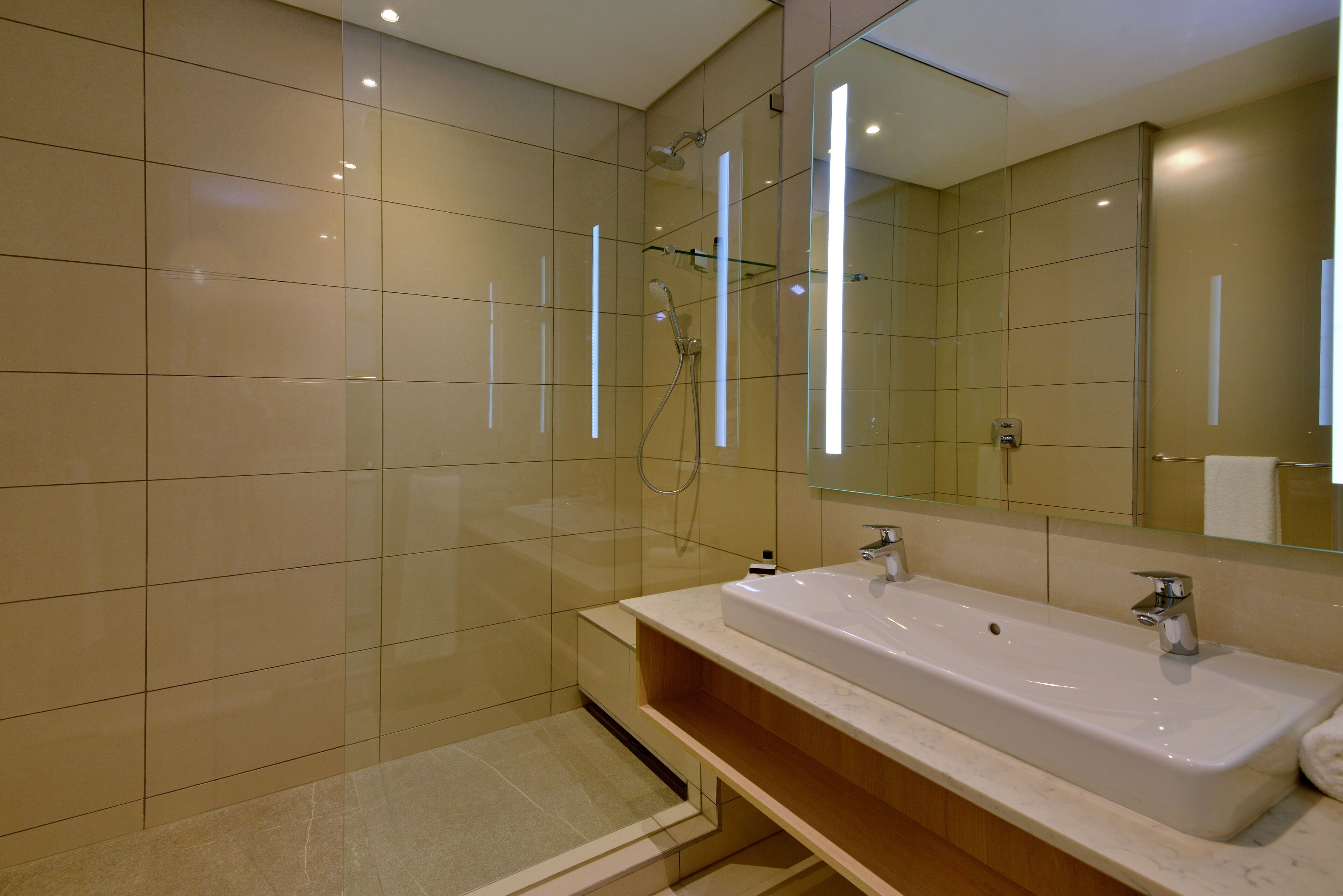 Un baño moderno con un lavamanos grande, espejo y cabina de ducha con paredes de vidrio.