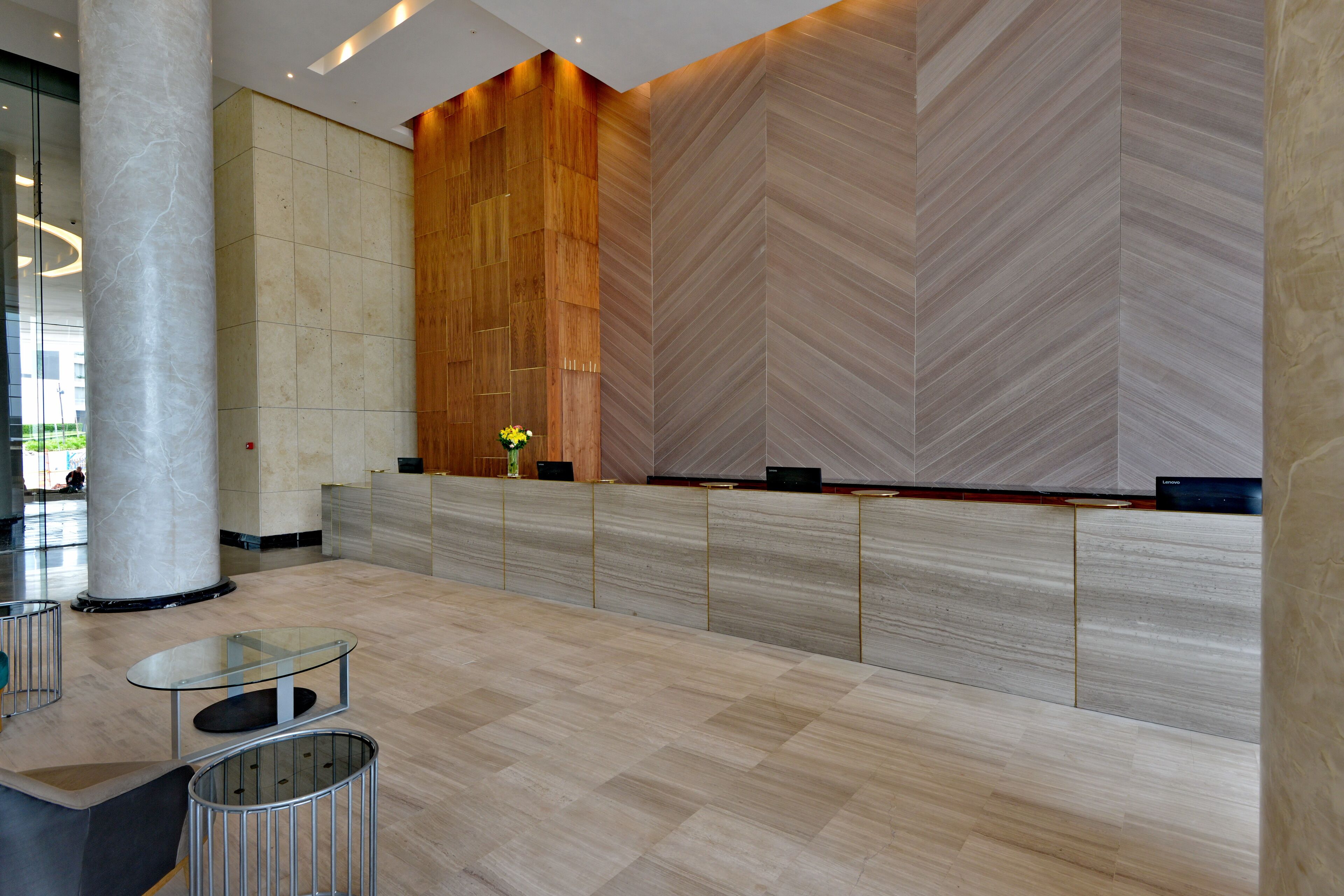 En moderne lobby med en marmorsøjle, en receptionsdisk og en væg med et fiskebensmønster.