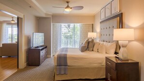 A hotel room with a bed, bedside lamps, a TV, a dresser, and a ceiling fan.