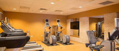 Un gimnasio con cintas de correr, elípticas y máquinas de pesas.