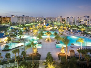 A resort with multiple swimming pools, palm trees, and a large building complex in the background. - Stunning Apartment - Gated Resort Near Theme Parks (Orlando)