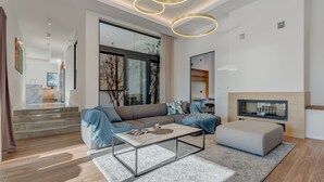 A modern living room with a sectional sofa, a coffee table, a TV, and a staircase leading to another level. - Sea Bliss Luxury Villa - Sevid (Marina)