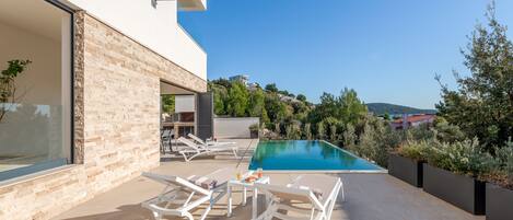 A modern outdoor pool area with lounge chairs and a clear view of the surrounding landscape.