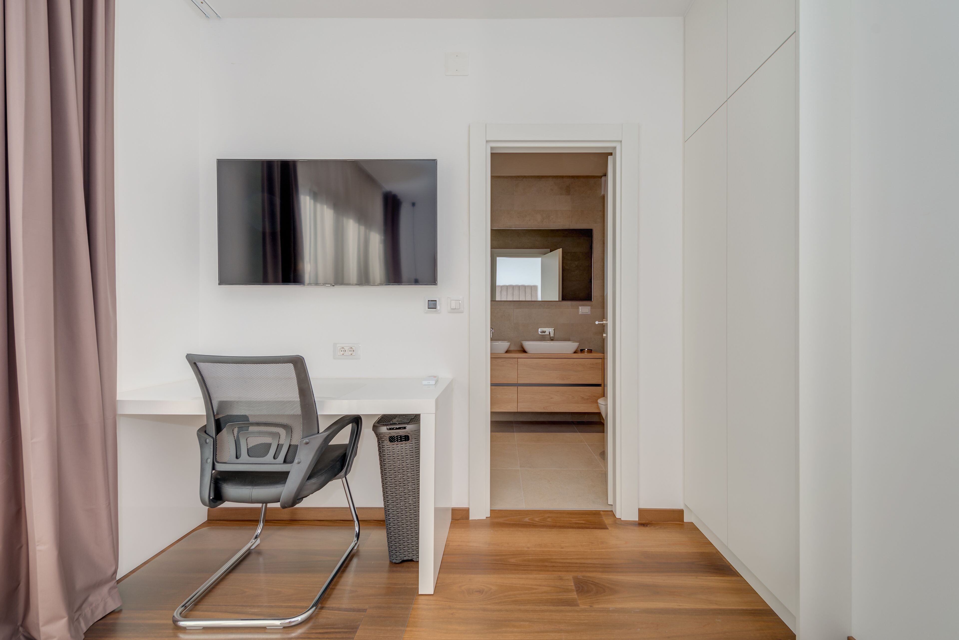 A modern office space with a desk, chair, and a television mounted on the wall.