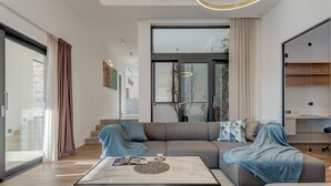 A modern living room with a sectional sofa, a glass coffee table, and a large window offering a view of the outdoors. - Sea Bliss Luxury Villa - Sevid (Marina)