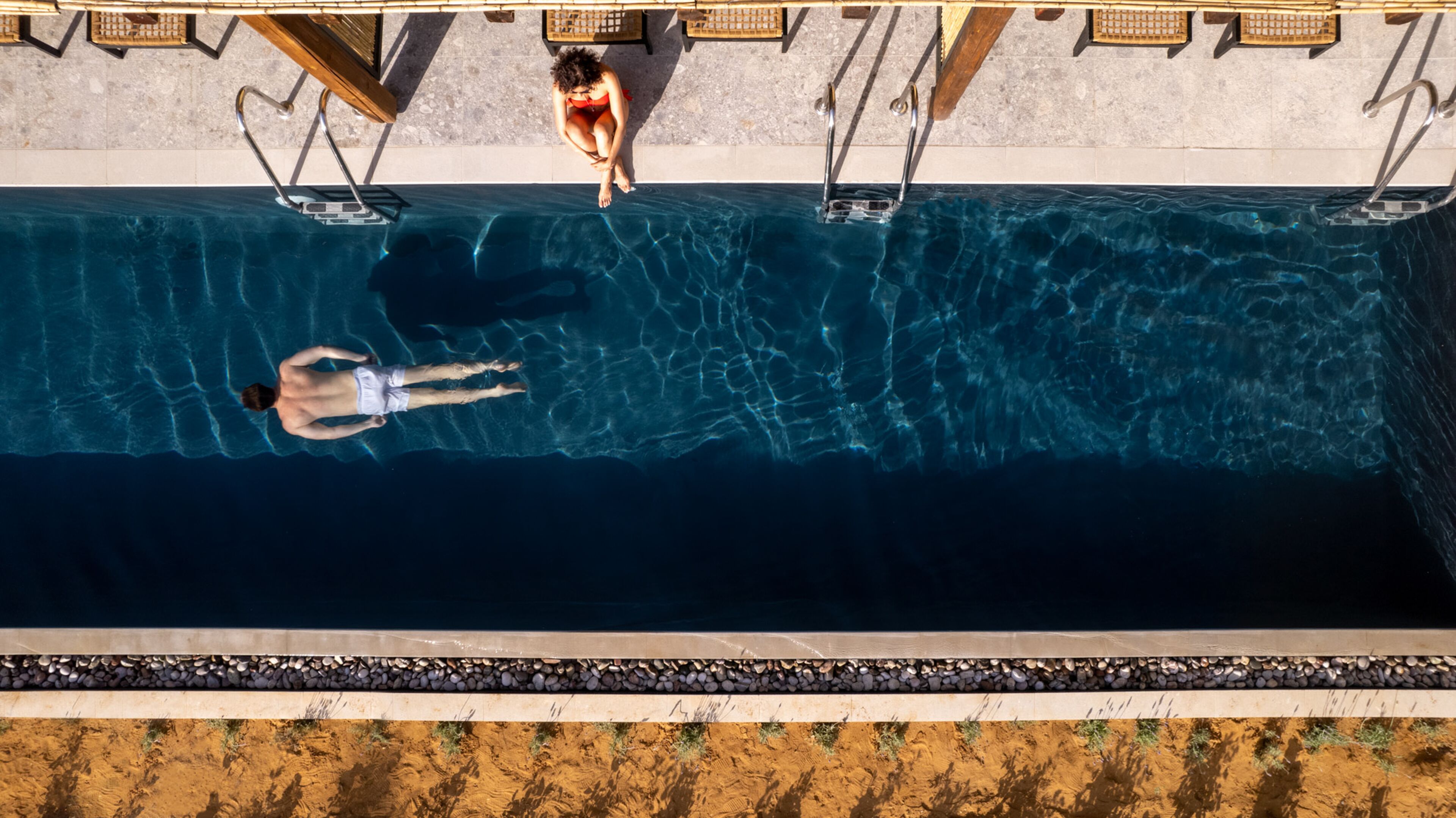 Una piscina con acqua cristallina, un trampolino e una zona relax con sedie.