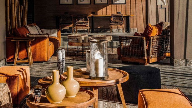 Ein modernes Wohnzimmer mit Weidenleuchten, einem Sofa, einem Couchtisch und einem gemusterten Teppich.