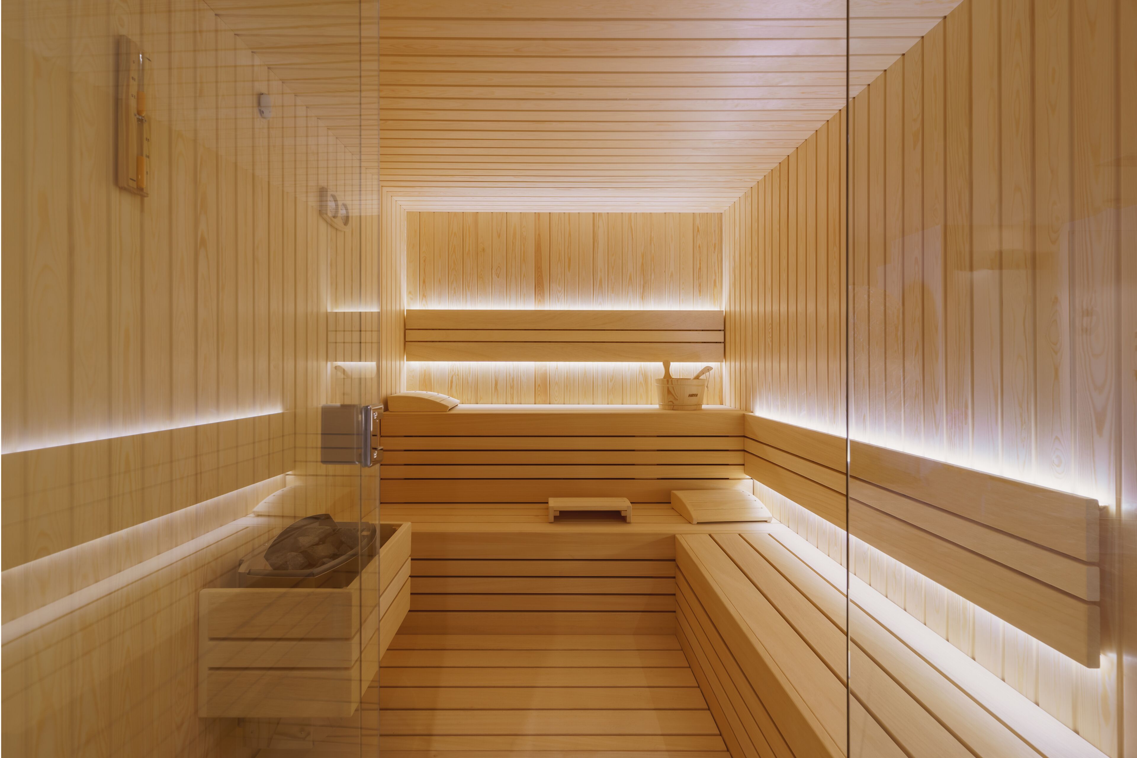 Una sauna moderna con listones de madera, un banco, una pequeña mesa y un banco con una toalla.