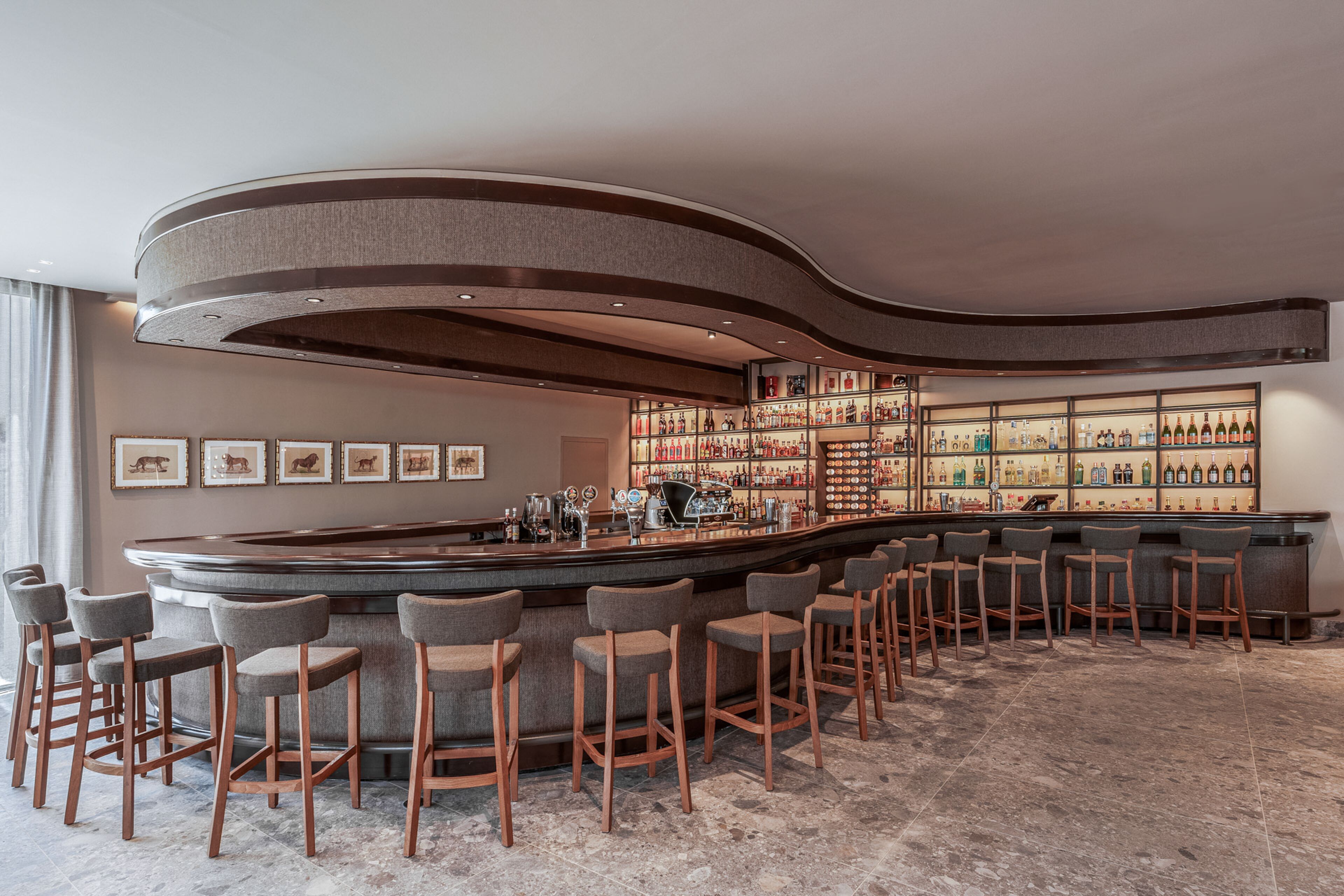 A bar area with a curved ceiling, a long bar counter, and multiple bar stools.