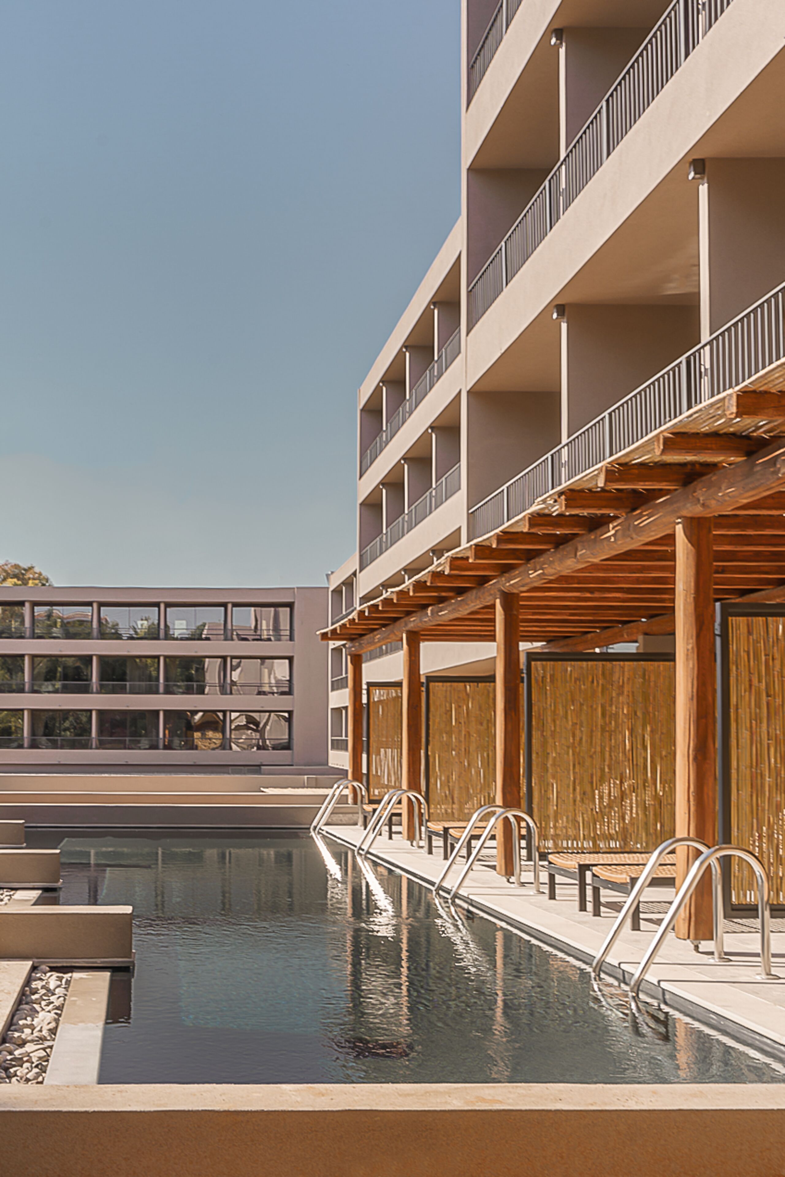 Un edificio moderno con piscina, terraza de madera y varios balcones.
