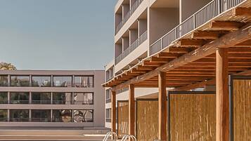 Un edificio moderno con piscina, terraza de madera y varios balcones.