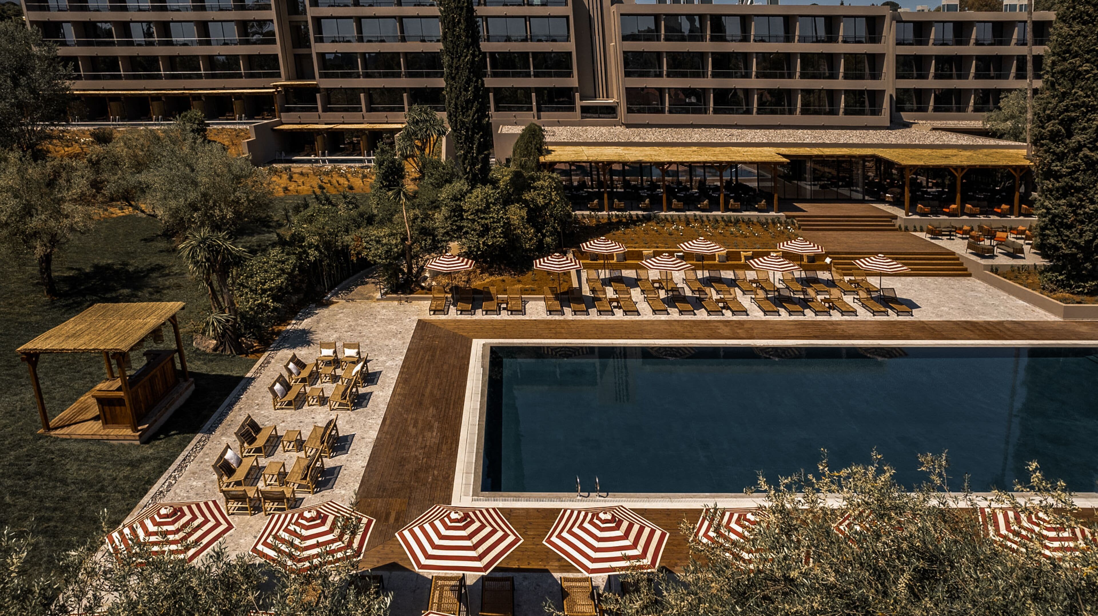 A hotel with a large swimming pool, sun loungers, and outdoor seating areas.