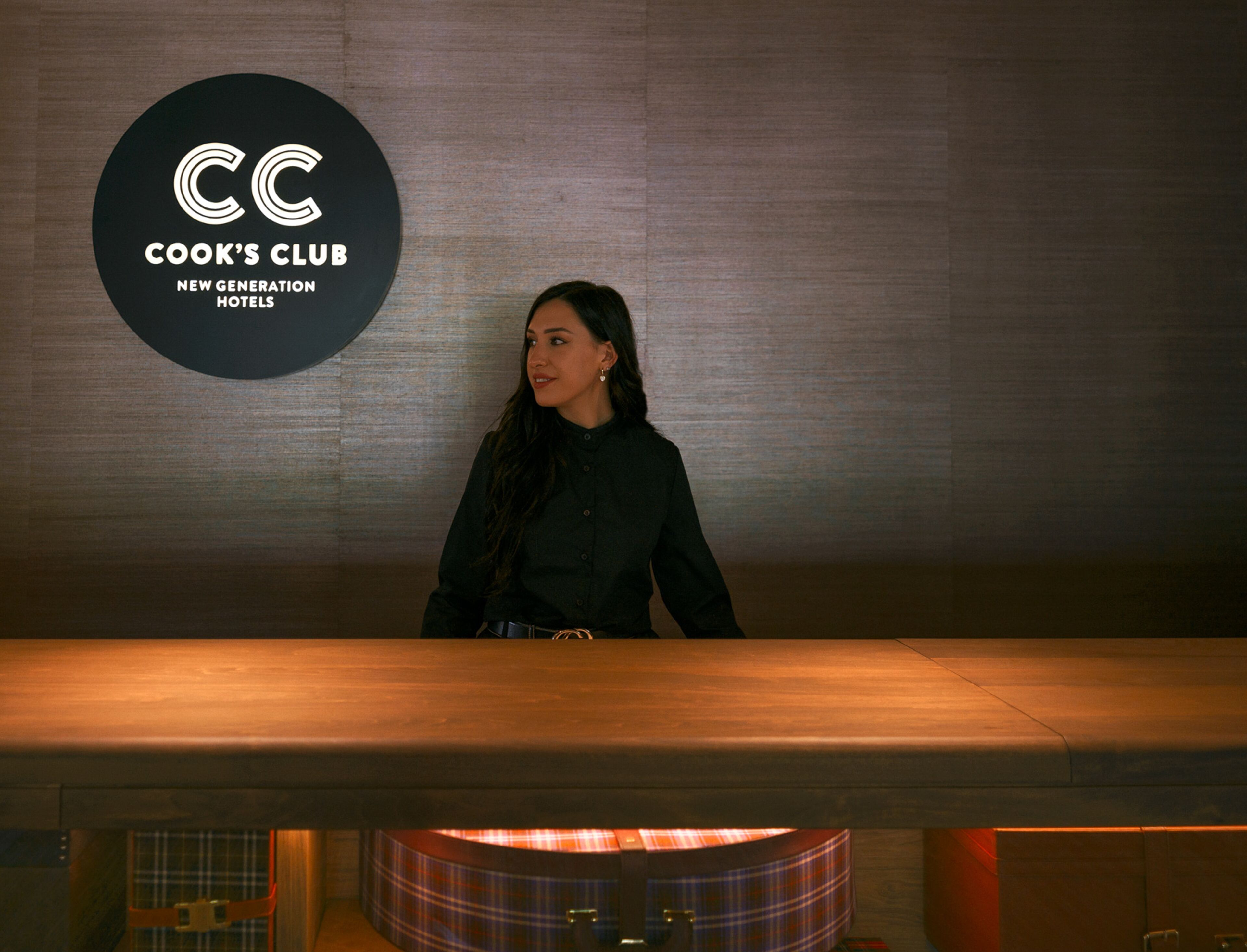 En kvinna står framför en skylt med texten: ”CC Cook’s Club – en ny generation hotell”.