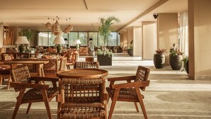 A spacious indoor area with wicker furniture, large potted plants, and hanging lamps. - Cook's Club Corfu - Adults Only (Corfu)